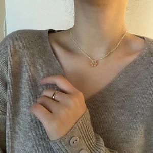 Collier délicat en perles de crème avec pendentif fleur de pêche et bague dorée sur mannequin