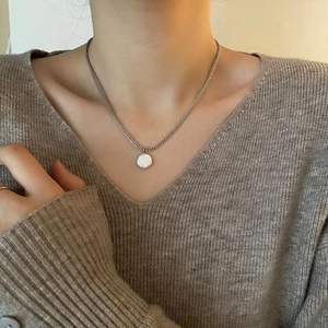 Minimalistische zilveren ketting met een gepolijste ronde hanger op een vrouwelijk model