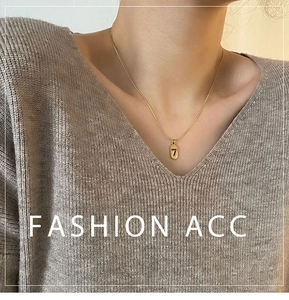 Detail of minimalist gold-plated titanium necklace featuring lucky number 7 pendant on model