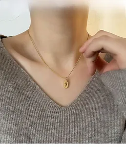 Close-up of gold titanium steel necklace featuring a lucky number 7 oval pendant on a model