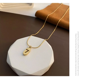 Close-up of minimalist gold titanium steel necklace featuring a hollow number 7 pendant