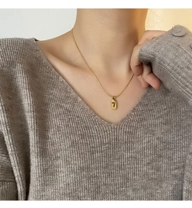 Close-up of minimalist gold titanium steel necklace featuring a hollow lucky number 7 pendant