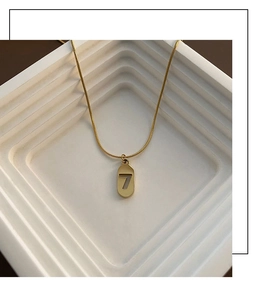 Macro detail of gold snake chain with an oval pendant featuring a cutout number 7