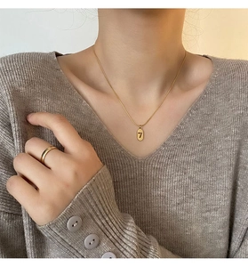 Close-up of gold titanium steel necklace with number 7 pendant and matching ring