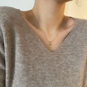 Minimalist titanium steel necklace with lucky number 7 oval pendant worn by a model