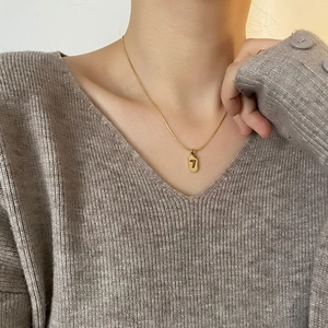 Minimalist gold titanium steel necklace featuring a lucky number 7 oval pendant on a model