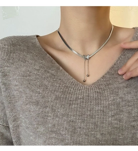 Gros plan d'un collier pendentif papillon argenté avec pompons élégants porté par un mannequin
