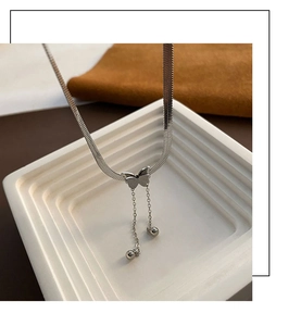 Détail du pendentif papillon argenté avec pampilles sur une chaîne serpent plate