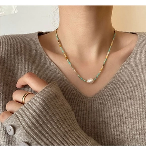 Macro detail of vintage beaded necklace with baroque pearl on ribbed knit sweater