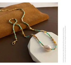 Close-up of baroque pearl pendant on colorful beaded necklace with gold accents