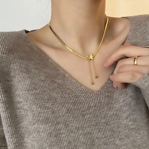 Élégant collier papillon doré 18 carats avec chaîne serpent et pompons porté par mannequin