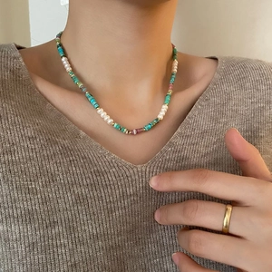 Detail of bohemian clavicle necklace with blue turquoise, white pearls and gold beads