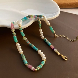 Detail of beaded necklace featuring blue turquoise and white pearls with gold lobster clasp