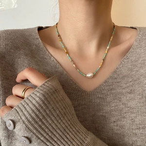 Boho layered baroque pearl necklace with colorful beads on a grey knitted sweater