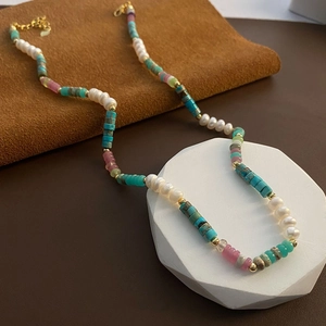 Bohemian choker necklace with natural pearls and turquoise beads on a display stand
