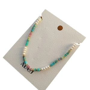Handmade necklace with natural blue pearls and colorful beads on a white card
