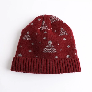 Detail of red knit beanie featuring white Christmas tree patterns and ribbed cuff design