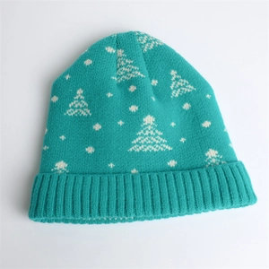 Detail of teal winter beanie with white jacquard knit snowflake and pine tree patterns