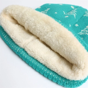 Close-up of winter knit hat with warm white fleece lining and turquoise snowflake pattern