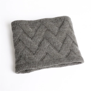 Détail d'un tour de cou en tricot gris montrant un tissage à chevrons épais et doux