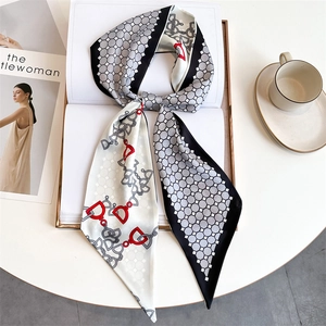 Close-up of printed silk-like scarf with equestrian chain motifs on lifestyle background