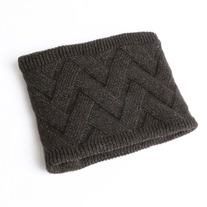 Détail d'un cache-col en maille épaisse marron foncé avec bords côtelés et motif panier