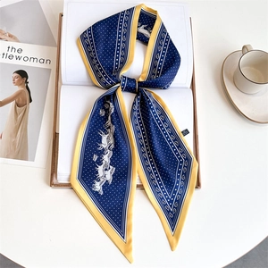 Detail of blue printed silk scarf with horse patterns on book with coffee cup