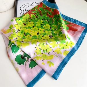 Detail of floral silk scarf with vibrant green patterns and sleek blue border