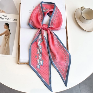 Detail of coral silk scarf tied in a bow on a book with horse and polka dot patterns