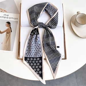Macro detail of houndstooth silk-like neck scarf tied over an open book and magazine