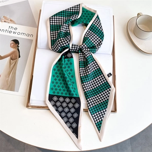 Detail of emerald green and houndstooth silk scarf on a book for a chic lifestyle look