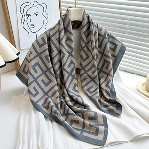 Detail of geometric pattern scarf styled over a white silk blouse with natural light shadow