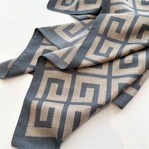 Macro detail of twill silk scarf showing geometric G-pattern and luxury smooth texture