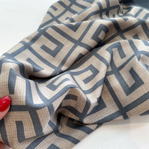 Detail of silk-like scarf featuring grey geometric patterns and elegant fabric texture