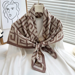 Silk scarf with geometric interlocking patterns worn on a white shirt in a modern room