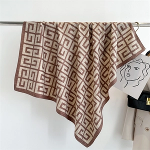 Detail of printed silk scarf with geometric pattern draped over a stylish beige blazer