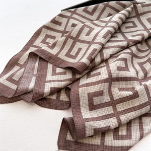 Detail of luxurious brown and beige geometric silk scarf with intricate twill texture