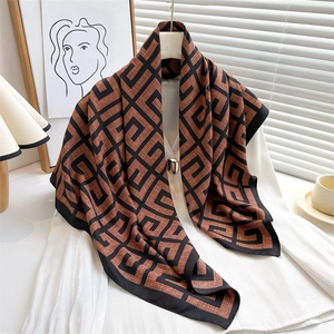 Detail of silk scarf with brown geometric maze pattern draped over a white blouse