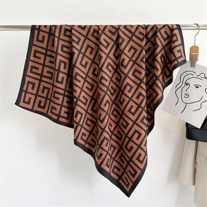 Detail of silk satin scarf with geometric pattern draped on a modern hanger in a studio