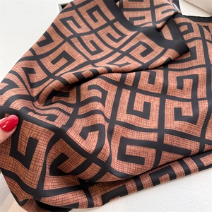 Close-up of geometric pattern silk scarf showing soft twill fabric texture and drape