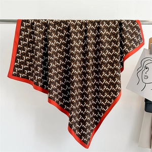 Detail of silk scarf showing geometric L-pattern and vibrant red borders with soft drape