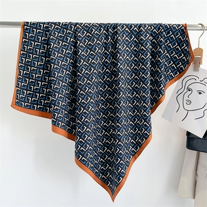 Detailed texture of luxury silk scarf with geometric letter print and brown borders