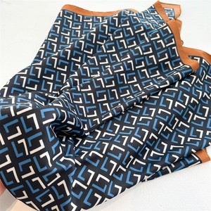 Close-up of geometric pattern twill silk scarf with luxury letter print and brown borders