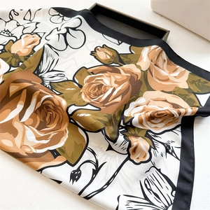 Close-up of elegant rose print silk scarf with black borders and orange floral pattern