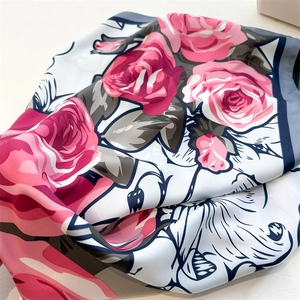 Detailed view of silk rose flower print scarf featuring smooth texture and rolled edges