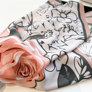 Detailed close-up of premium silk scarf with elegant orange rose floral print