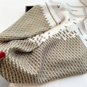 Detail of silk texture square scarf with elegant golden and brown monogram patterns