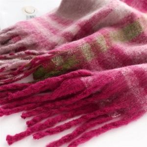 Close-up of thick winter scarf with pink and beige plaid texture and long tassels