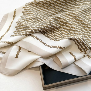 Detail of premium silk-like square scarf showing golden geometric knot patterns and soft satin luster