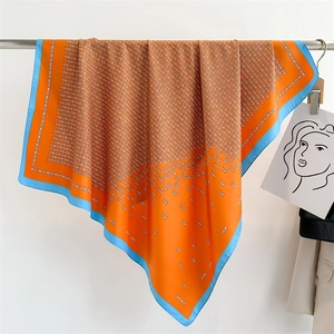 Close-up of orange and blue silk scarf with geometric chain pattern on a hanger